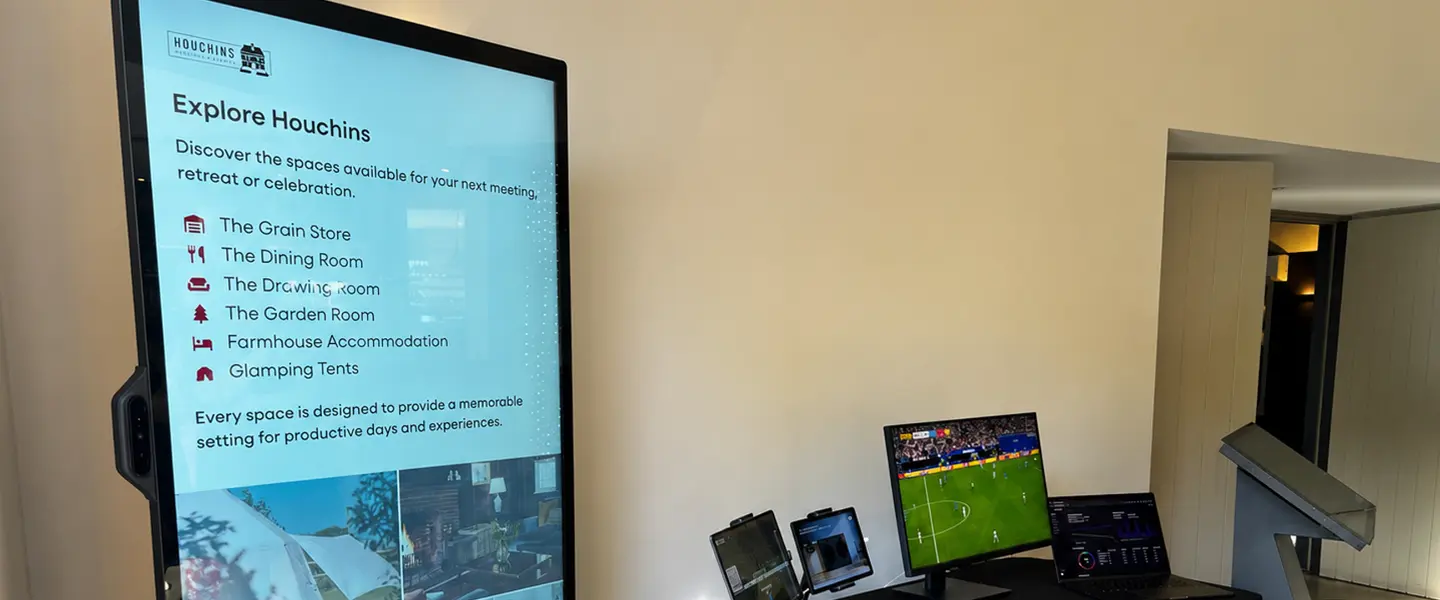 Explore Spaces digital signage with a football game setup in the background