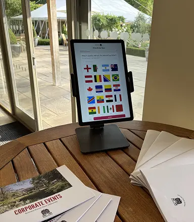 World Cup flags quiz game on a tablet next to corporate events brochures